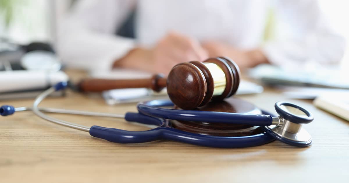gavel and stethoscope resting on table in front of a doctor